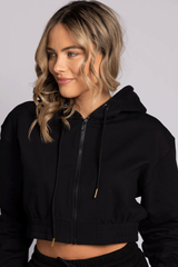 A woman wearing a black hoodie with a front pouch, showcasing a casual and relaxed fit.