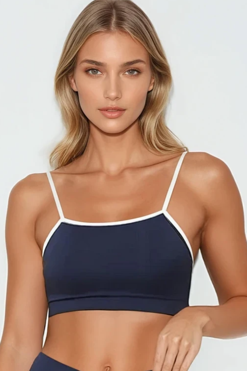 Woman wearing a navy sports bra and shorts set on a white background