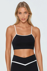 Woman wearing a black sports bra and shorts set with white sneakers on a white background