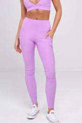 Woman wearing a pink sports bra and leggings set on a white background