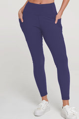 Person wearing purple leggings with white sneakers on a light gray background