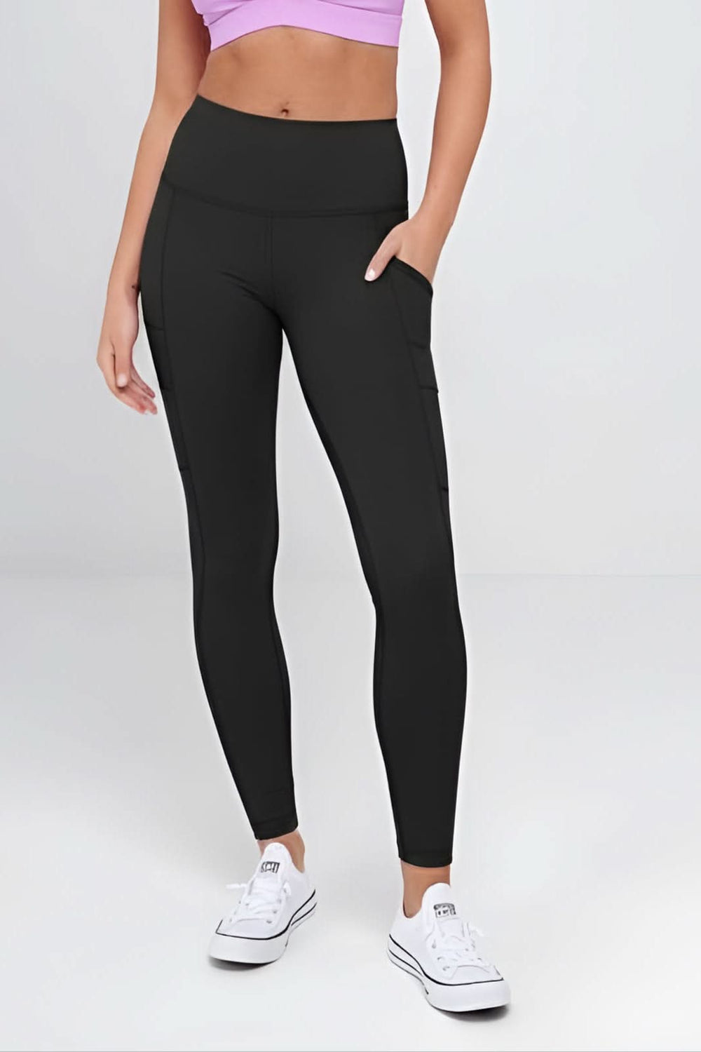 Woman wearing a purple sports bra and black leggings on a white background