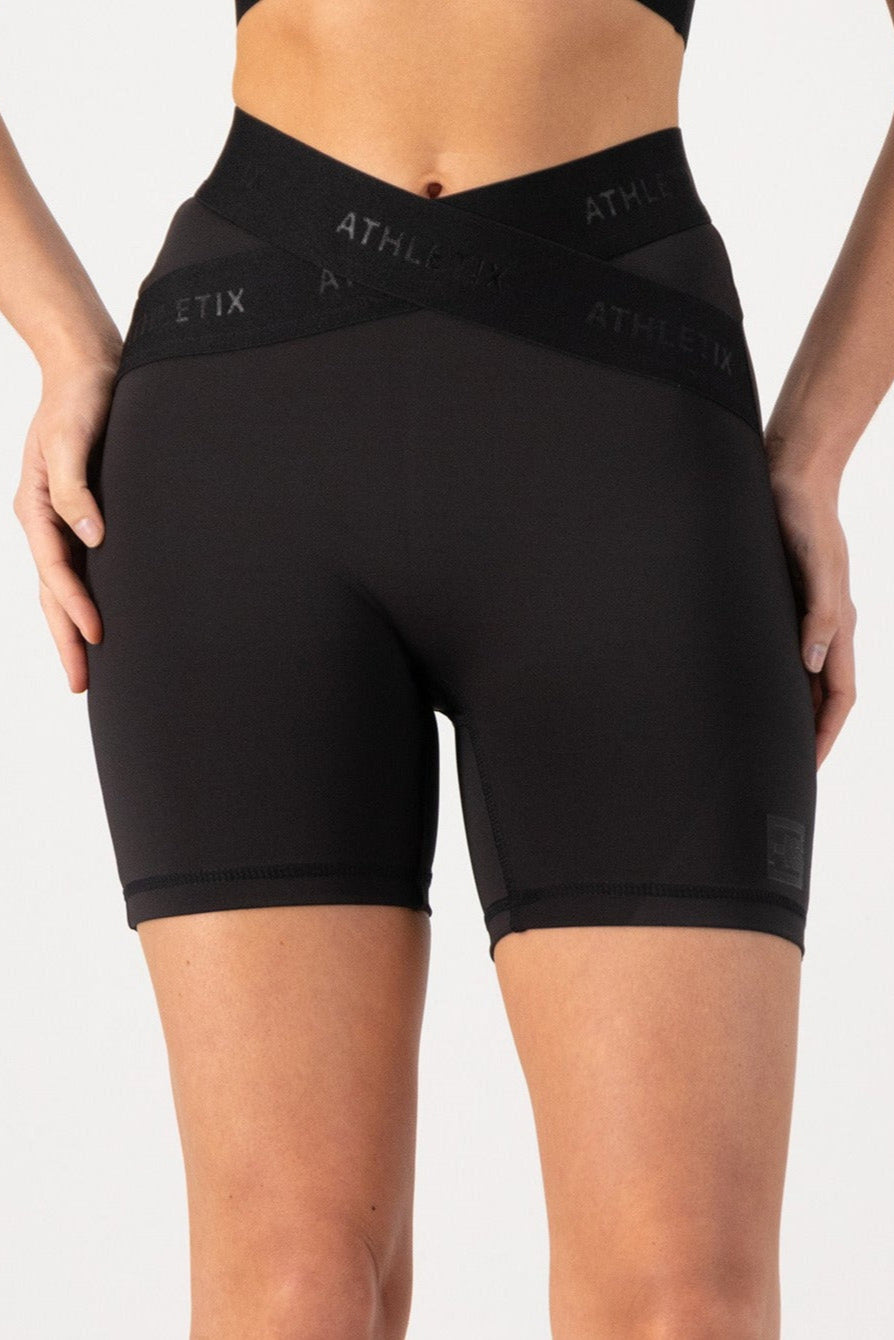 Athletic training shorts with an elasticated waistband and cross-over design, featuring a predominantly black color with the brand logo 'ATHLETIC' visible on the waistband.
