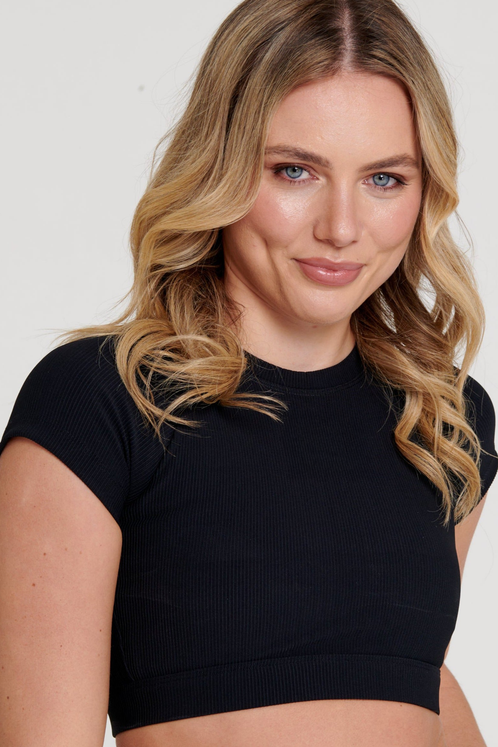 Woman wearing a black crop top against a plain background