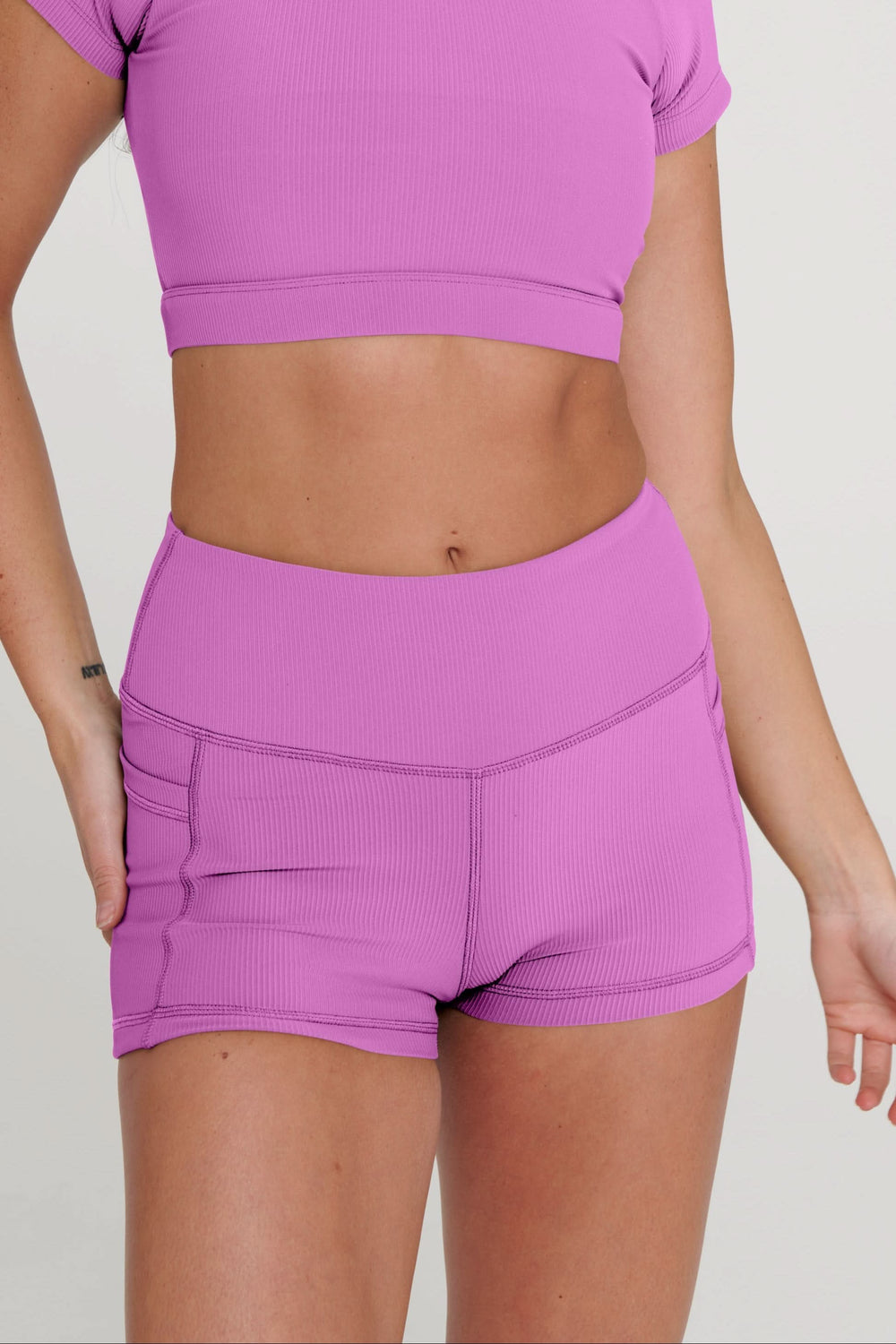 Woman wearing a purple athletic outfit with a logo on a plain background